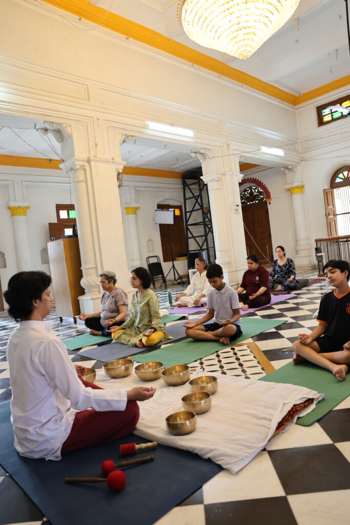 A beginner meditation class seated on mats with singing bowls, at the Parasha ashram in Rishikesh