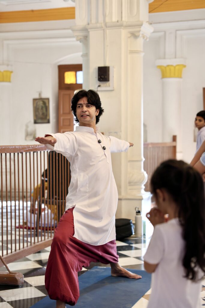 A teacher guiding a student through a seated posture